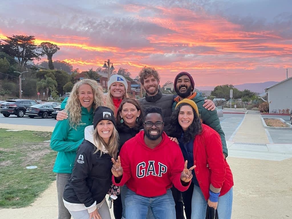 Amy and her bocce ball team pose for a picture in front of a beautiful sunset.