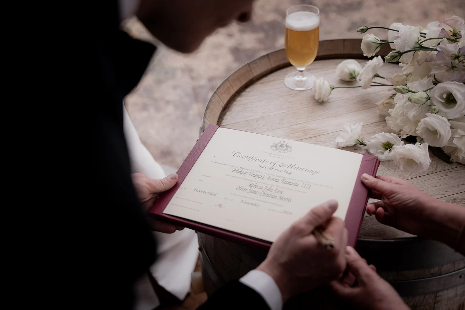A Certificate of Marriage resting on a wine barrel surrounded by white flowers