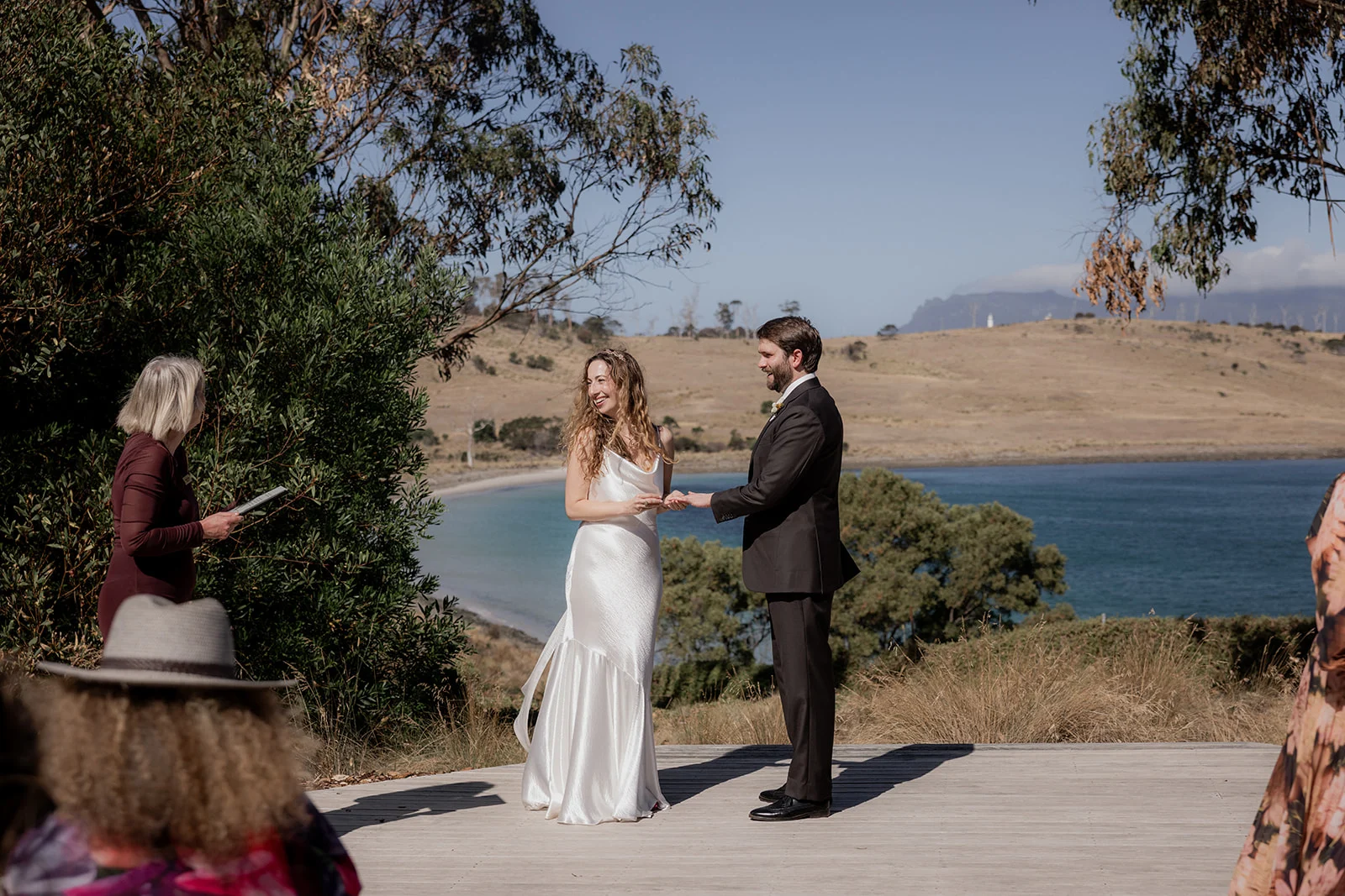A groom reading his personal wedding vows aloud to his bride under a floral arch