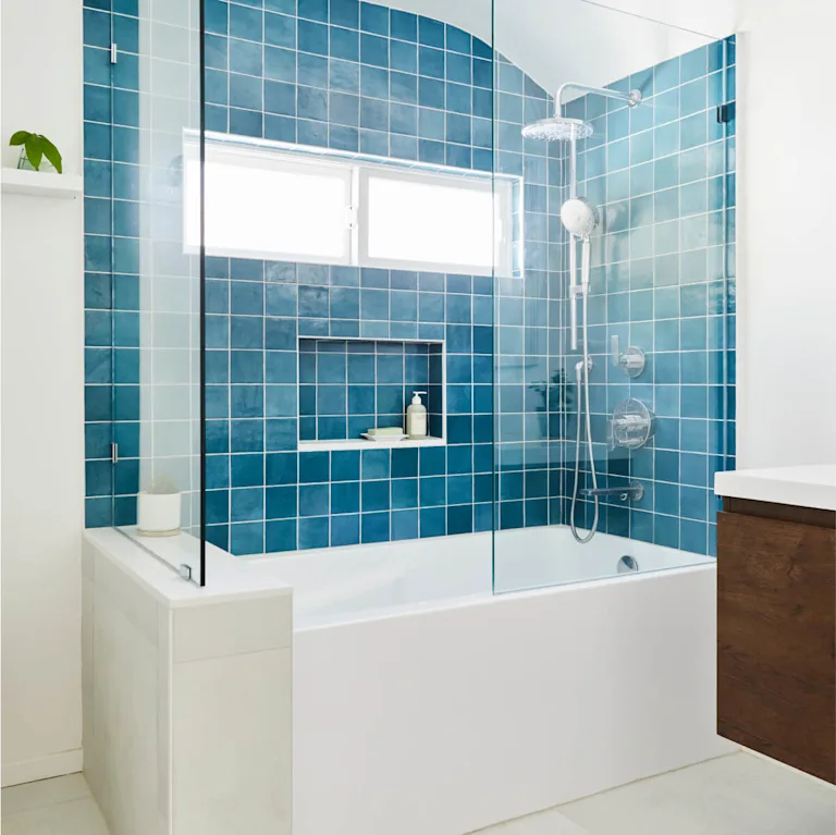 A tub and shower combo with blue tile and white bathtub