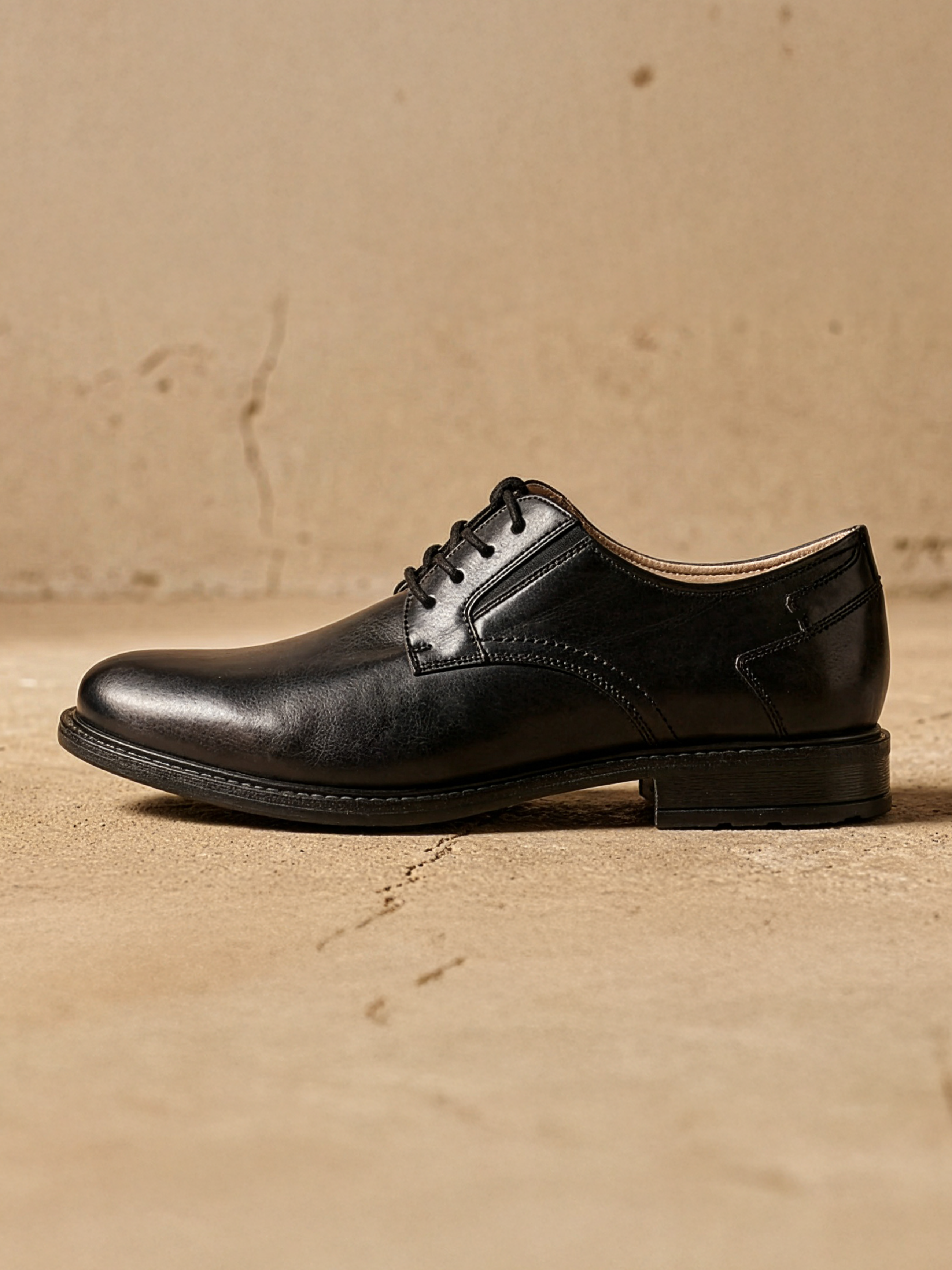 Scarpa stringata da uomo nera in pelle in vista laterale su sfondo beige