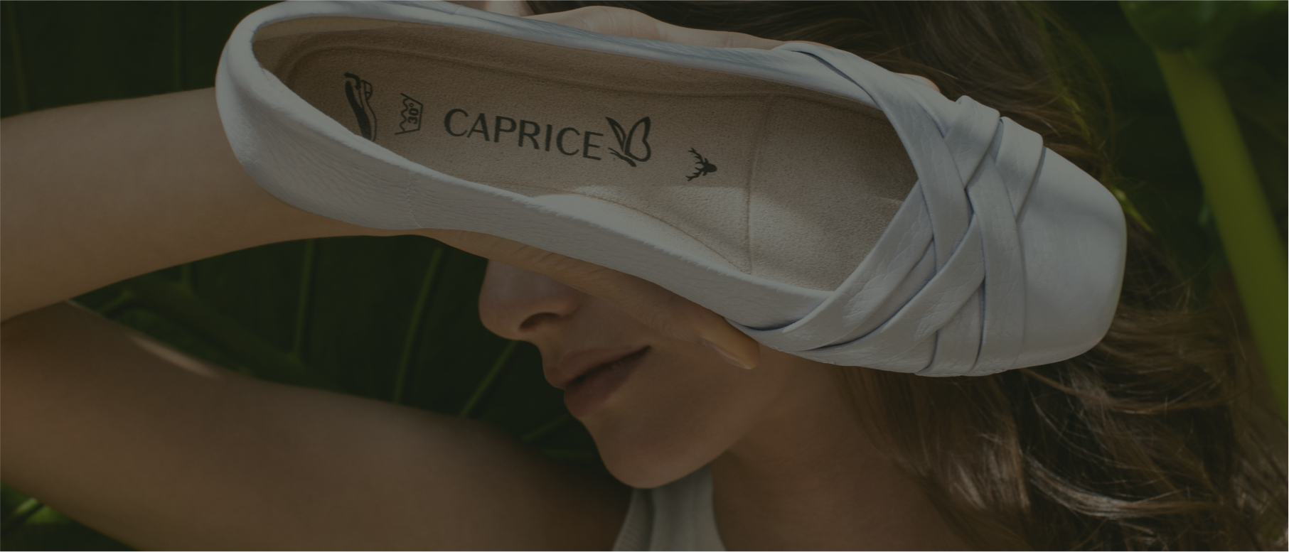 Una donna tiene una ballerina verso la fotocamera in modo che i simboli di manutenzione sulla suola siano visibili.