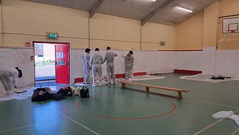 The sustainability and communications team painting at the Birmingham Settlement Sports and Community Centre