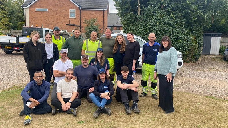 A group photo of the Airfield Engineering Team at Birmingham Airport volunteering, the team is sat on the grass outside 