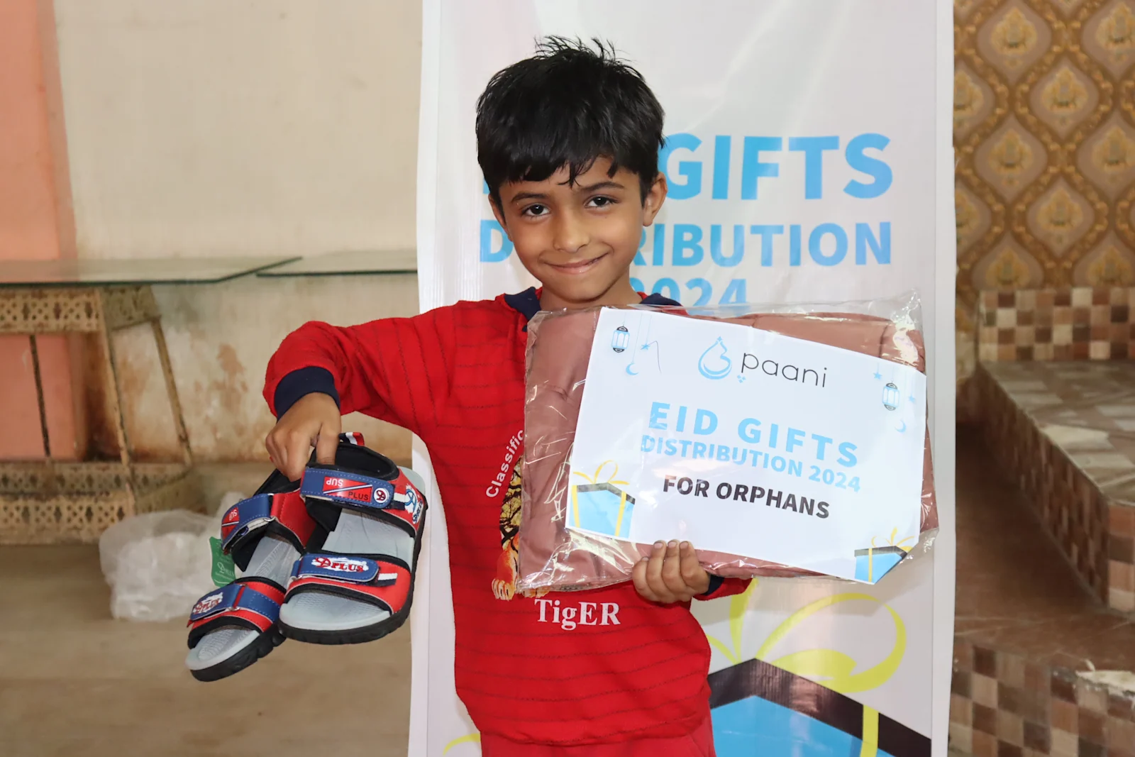 Boy holding his Eid gift box through Paani's Orphan Support Program in Pakistan