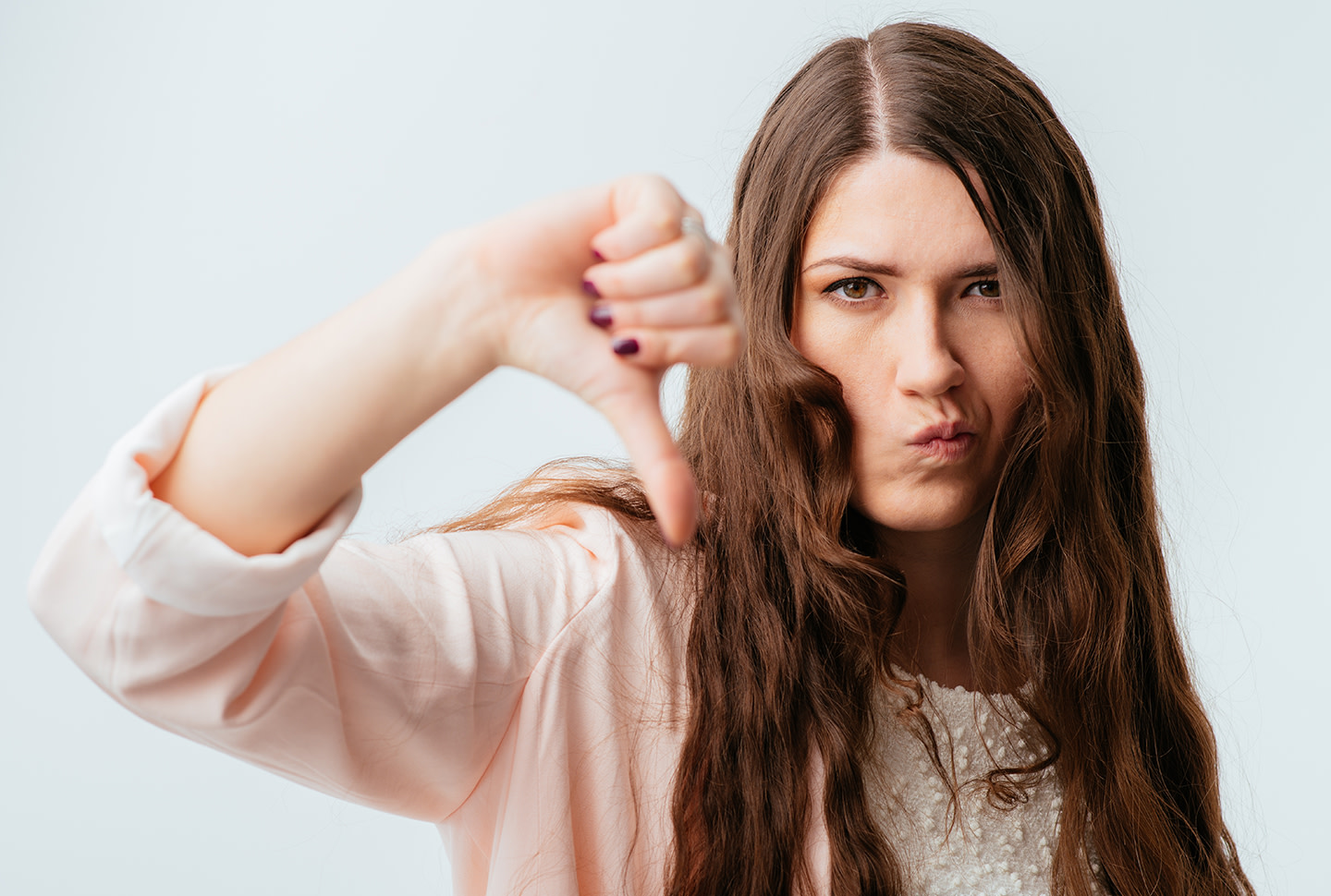 Chica morena de cabello largo con el cabello graso que muestra el pulgar hacia abajo aislado sobre un fondo blanco Chica morena de cabello largo con el cabello graso que muestra el pulgar hacia abajo aislado sobre un fondo blanco