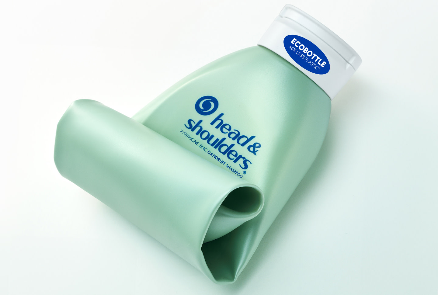 Botella doblada de champú ecológica verde claro vacía y rizada sobre un fondo blanco Botella doblada de champú ecológica verde claro vacía y rizada sobre un fondo blanco