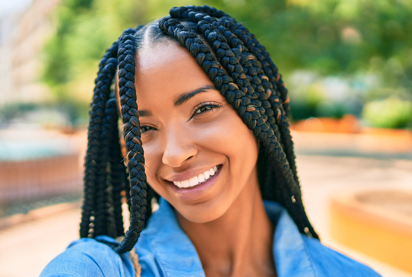 Joven afroamericana con trenzas sonriendo feliz tomándose una selfi con su cámara en el parque. Joven afroamericana con trenzas sonriendo feliz tomándose una selfi con su cámara en el parque.