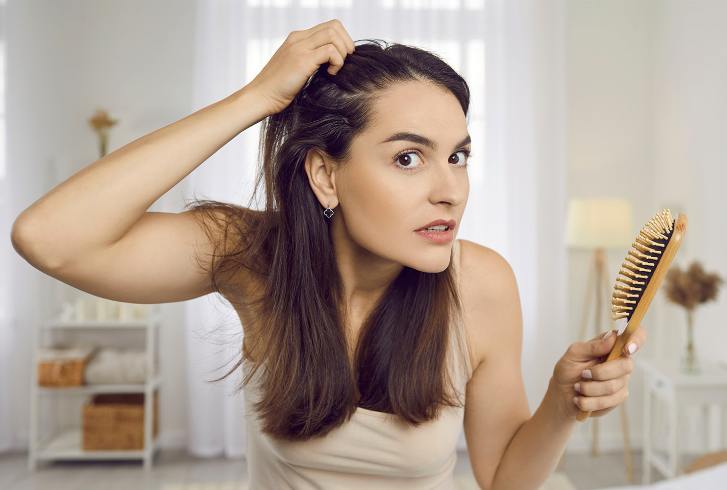 Retrato de una mujer en los años 30 mirando su reflejo con expresión nerviosa horrorizada mientras nota la caspa del cuero cabelludo y la acumulación de productos Retrato de una mujer en los años 30 mirando su reflejo con expresión nerviosa horrorizada mientras nota la caspa del cuero cabelludo y la acumulación de productos