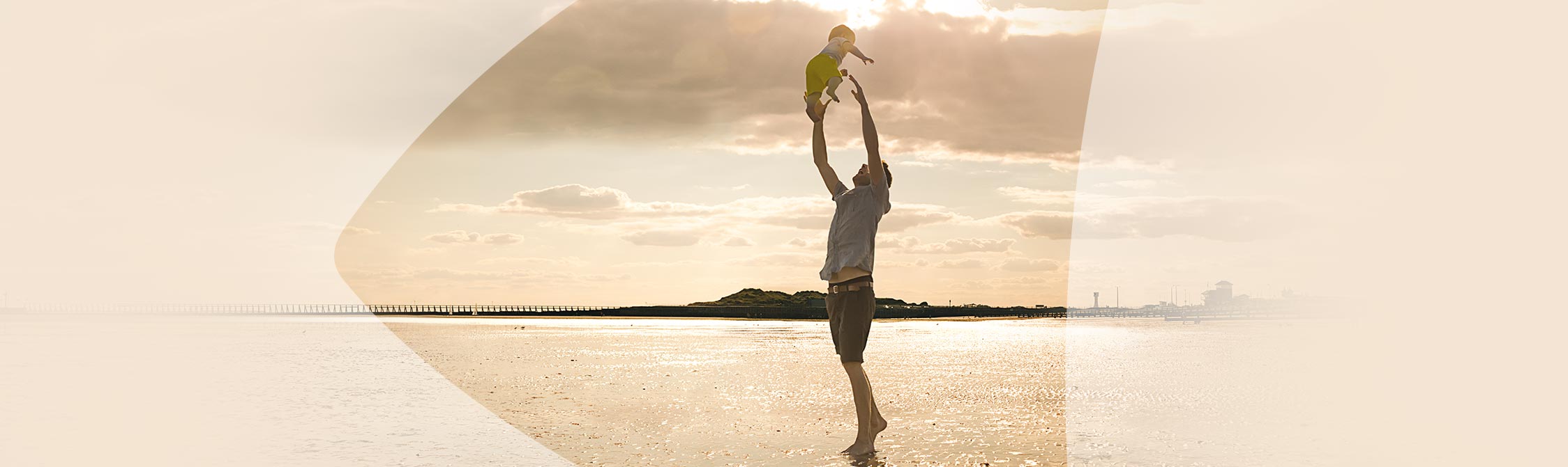 Mann spielt mit Kind am Strand