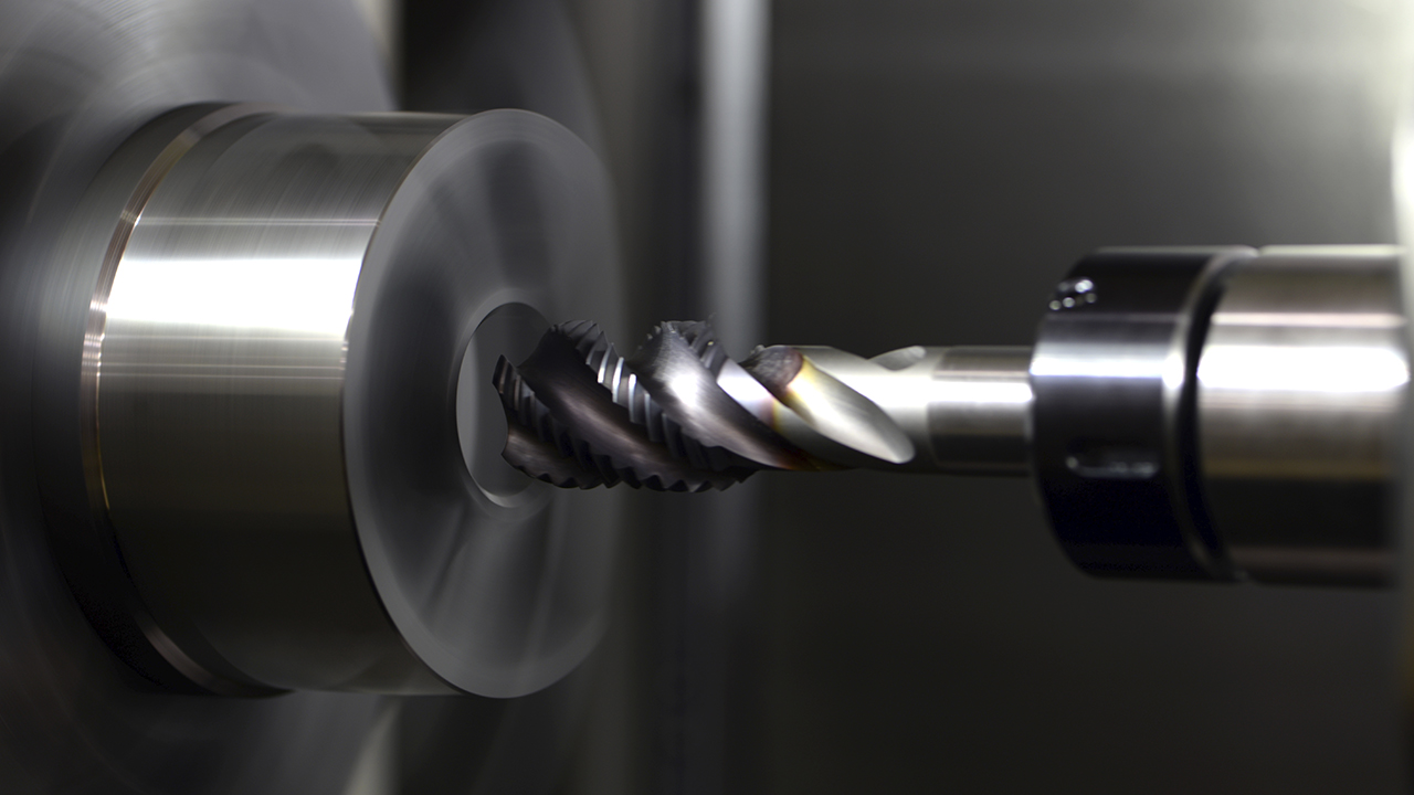 Spiral end mill drilling into a metallic cylindrical workpiece on a CNC machine 