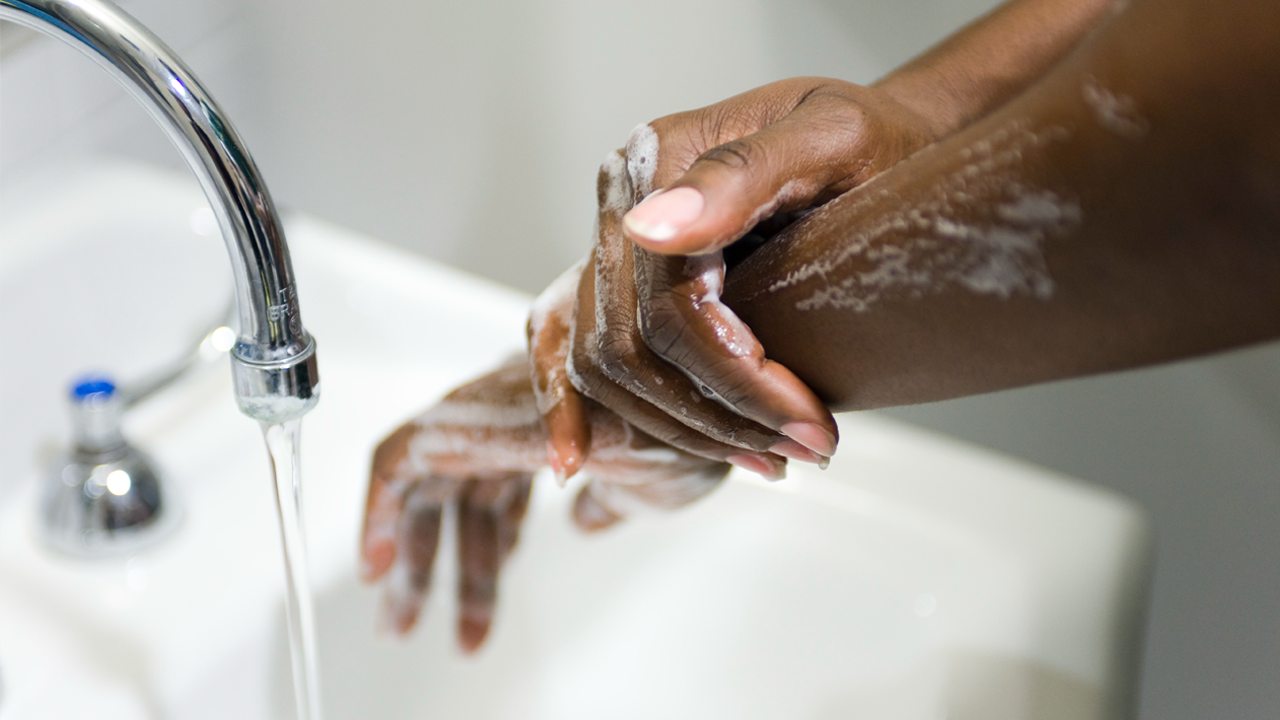 Person washing hands with soap under running water at a sink