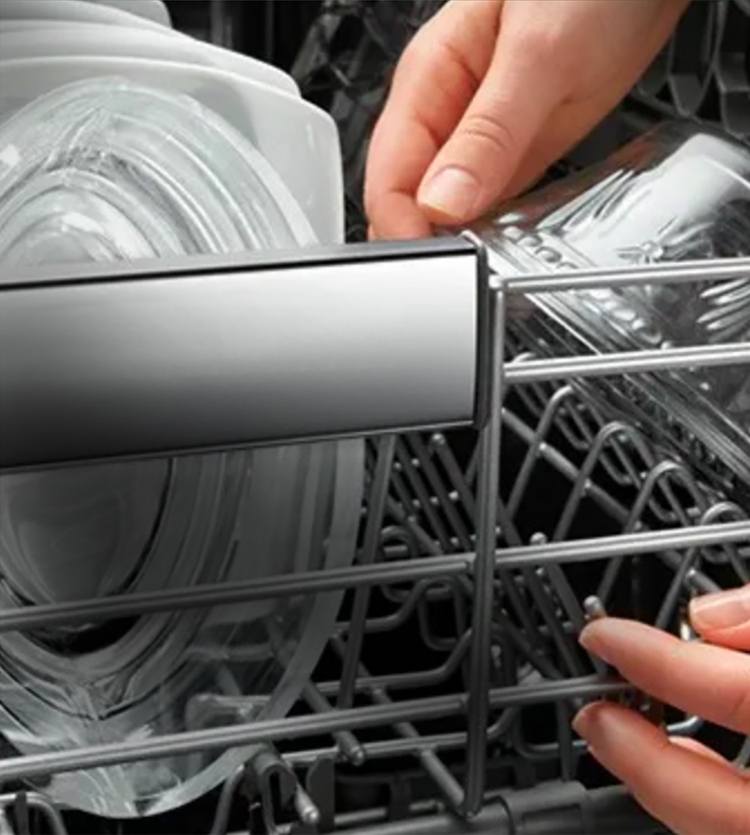 Person offloading clean glass dishware out of dishwasher