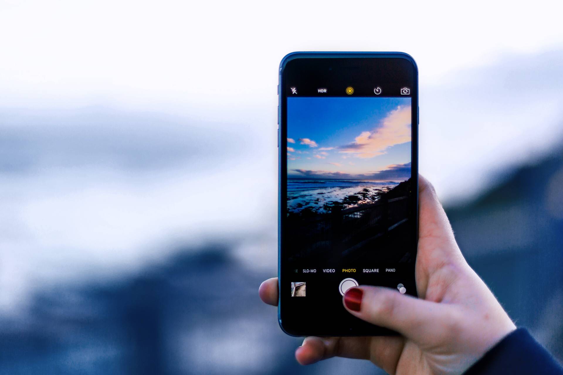En kvinna fotograferar en strand med sin mobil
