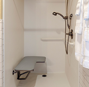 Interior of shower with hand rails and bench attached to wall.
