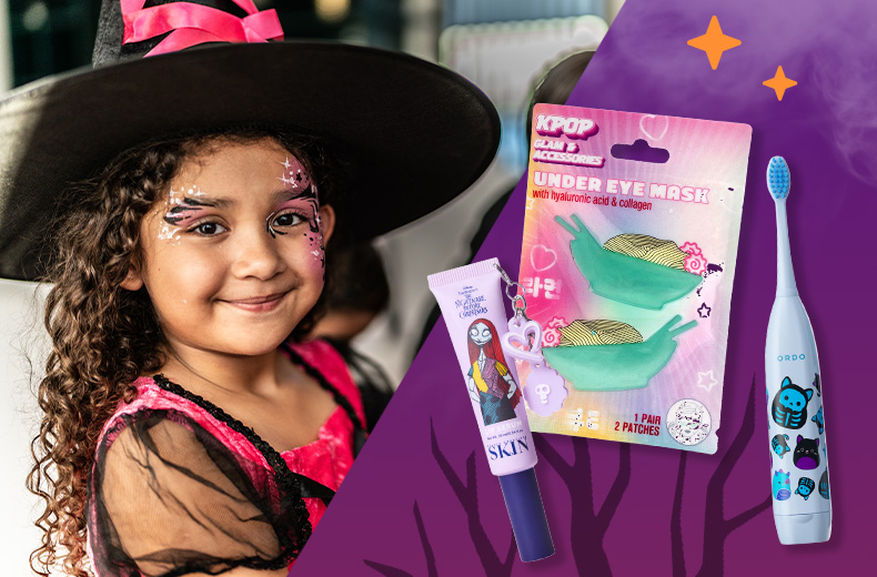 KPop Glam and Accessories Under Eye Mask patches, Skin's Nightmare Before Christmas lip serum and Halloween-themed Ordo electric toothbrush against a purple night sky background next to a child dressed as a witch for Halloween
