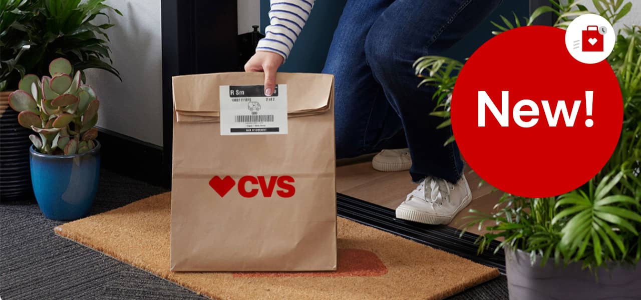 New! CVS shopping bag with clock pictogram, woman picking up a CVS Pharmacy delivery bag on a doorstep.