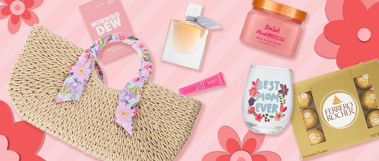 Ferrero Rocher chocolates, a woven straw handbag with a floral scarf, a small fragrance bottle, a "Best Mom Ever" glass, pink e.l.f. lip balm, a Morning Dew face mask and a Tree Hut Pink Hibiscus shea sugar scrub on a pink background with flowers.