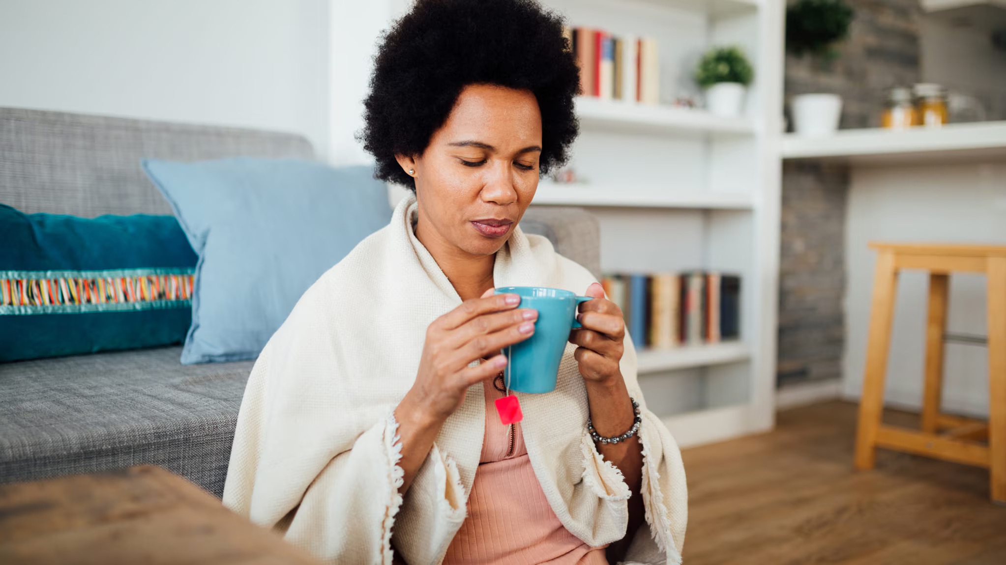 Woman drinking a cup of tea to soothe flu symptoms