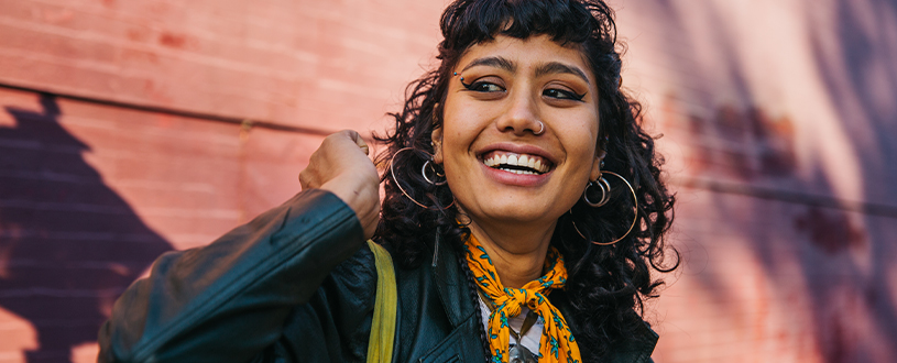 Young woman with healthy, curly hair laughing in the sunshine.