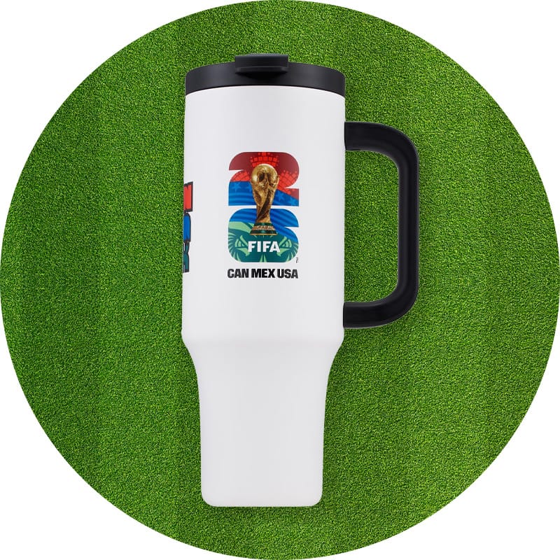 White and black travel tumbler with FIFA World Cup graphic with a trophy and "Can Mex USA" text set against a green grass background