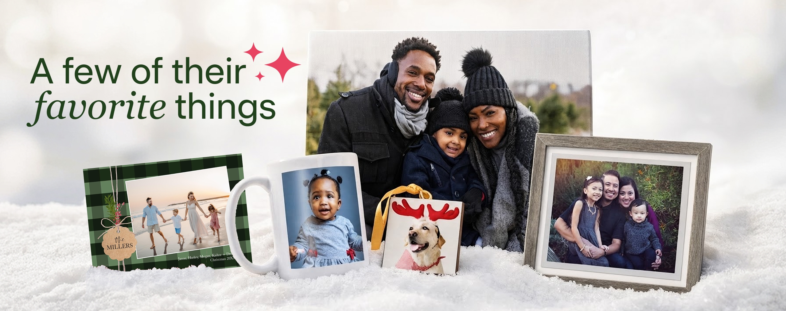 A few of their favorite things. Personalized photo gifts, including a mug with a baby photo, an ornament photo of a dog with reindeer antlers, a photo book, a framed family photo and a canvas family photo, all resting on a blanket of snow.