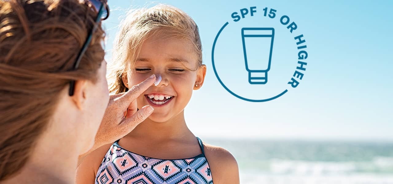 SPF 15 or higher logo, woman applying sunscreen to girl's nose