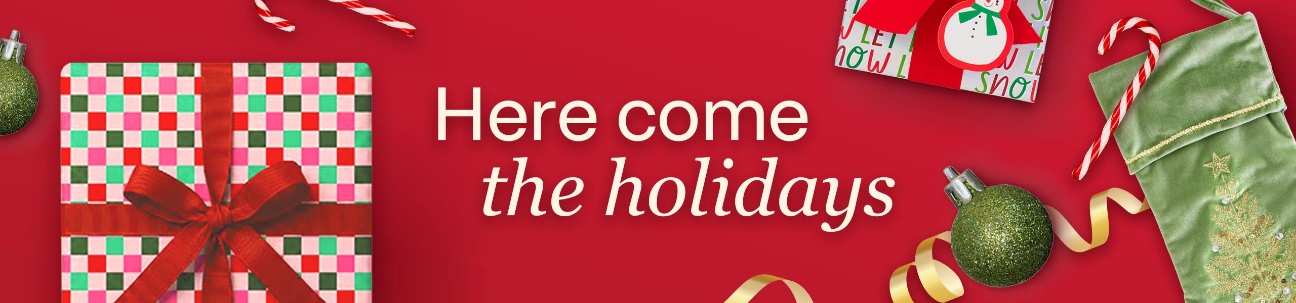 Here come the holidays. Holiday gifts wrapped in festive wrapping paper with gold ribbon, a green ornament, a green stocking with a Christmas tree on it and candy canes.