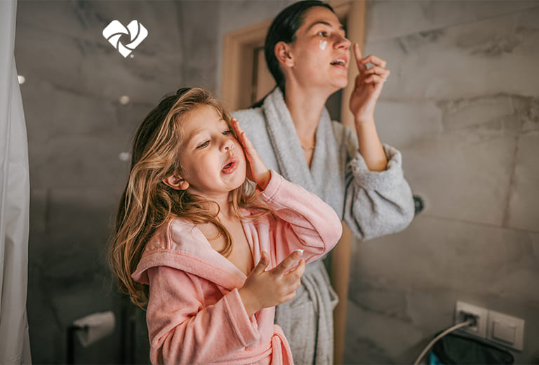 A parent and child applying lotion to their faces. Logo de Beauty Unaltered