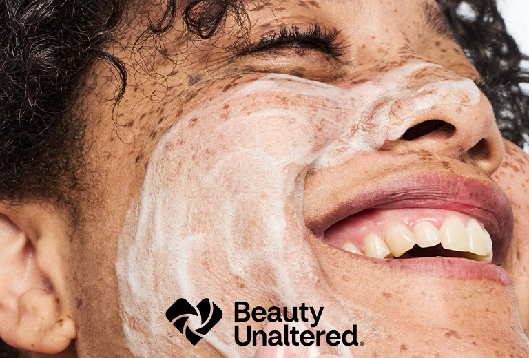Beauty Unaltered. Primer plano de una persona mirando hacia arriba con los ojos cerrados y espuma para el cuidado de la piel en el rostro.
