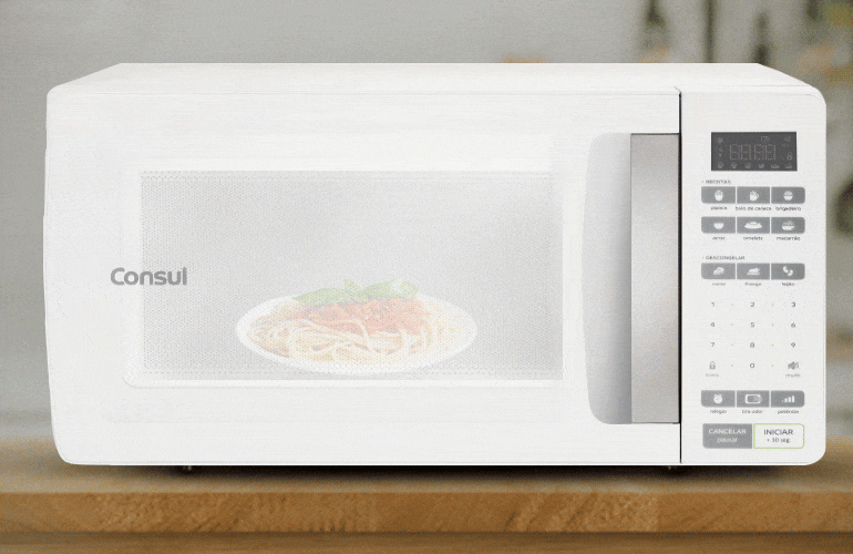 Micro-ondas em funcionamento com prato de macarronada dentro