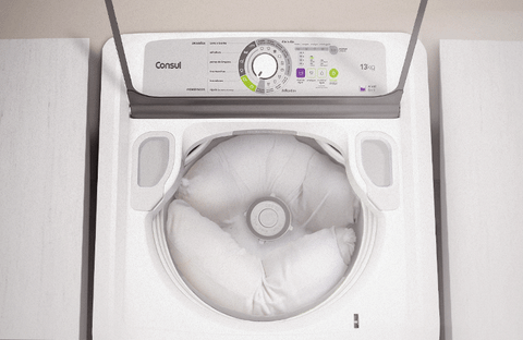 Uma máquina de lavar com um travesseiro dentro e o texto: Distribuia os travesseiros igualmente na lavadora