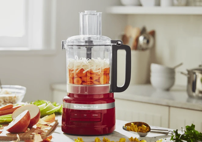 melhor processador de alimentos - Processador de Alimentos KitchenAid com cenouras em rodelas e cebolas picadas em seu interior.
