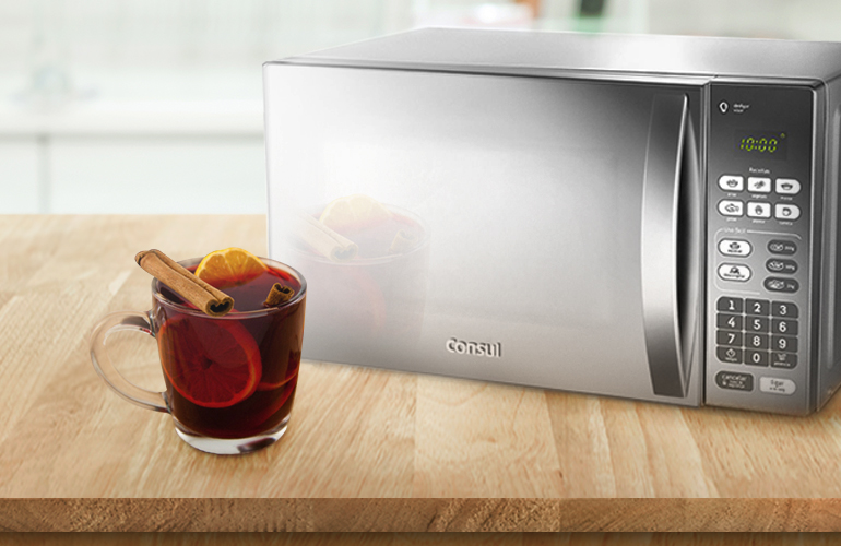 Um copo com vinho quente na frente de um micro-ondas