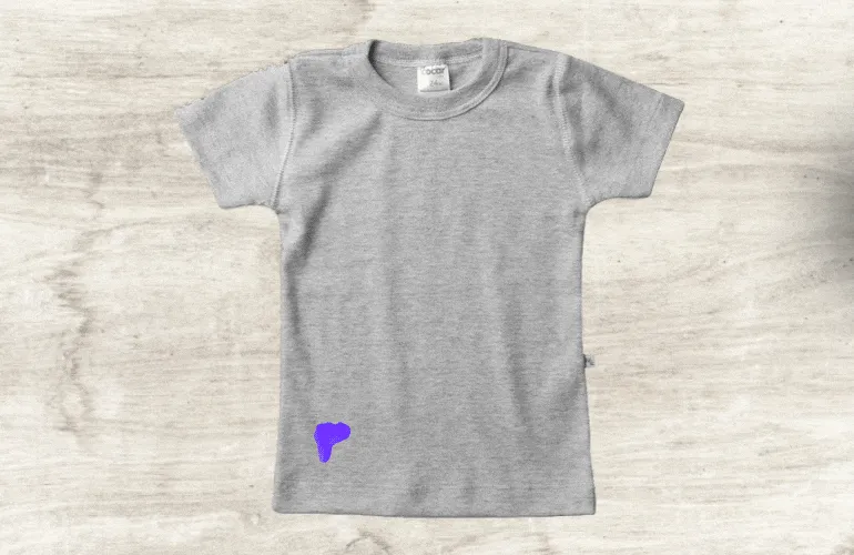 Algodão com removedor sendo colocado sobre mancha de esmalte na camiseta
