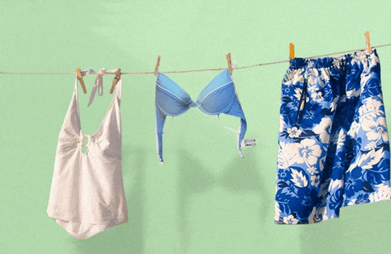 Vemos roupas de verão penduradas no varal, com destaque para a etiqueta das roupas.