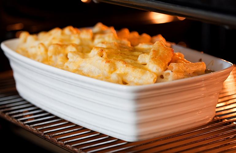 Macarrão do tipo penne em uma travessa branca em cima da grade do forno.