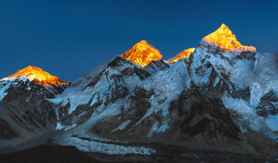 A photo showing a Himalayan mountain range with mount Everest in the background during a sunset.