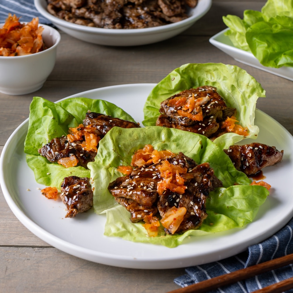 Korean BBQ pork lettuce wraps on a white plate