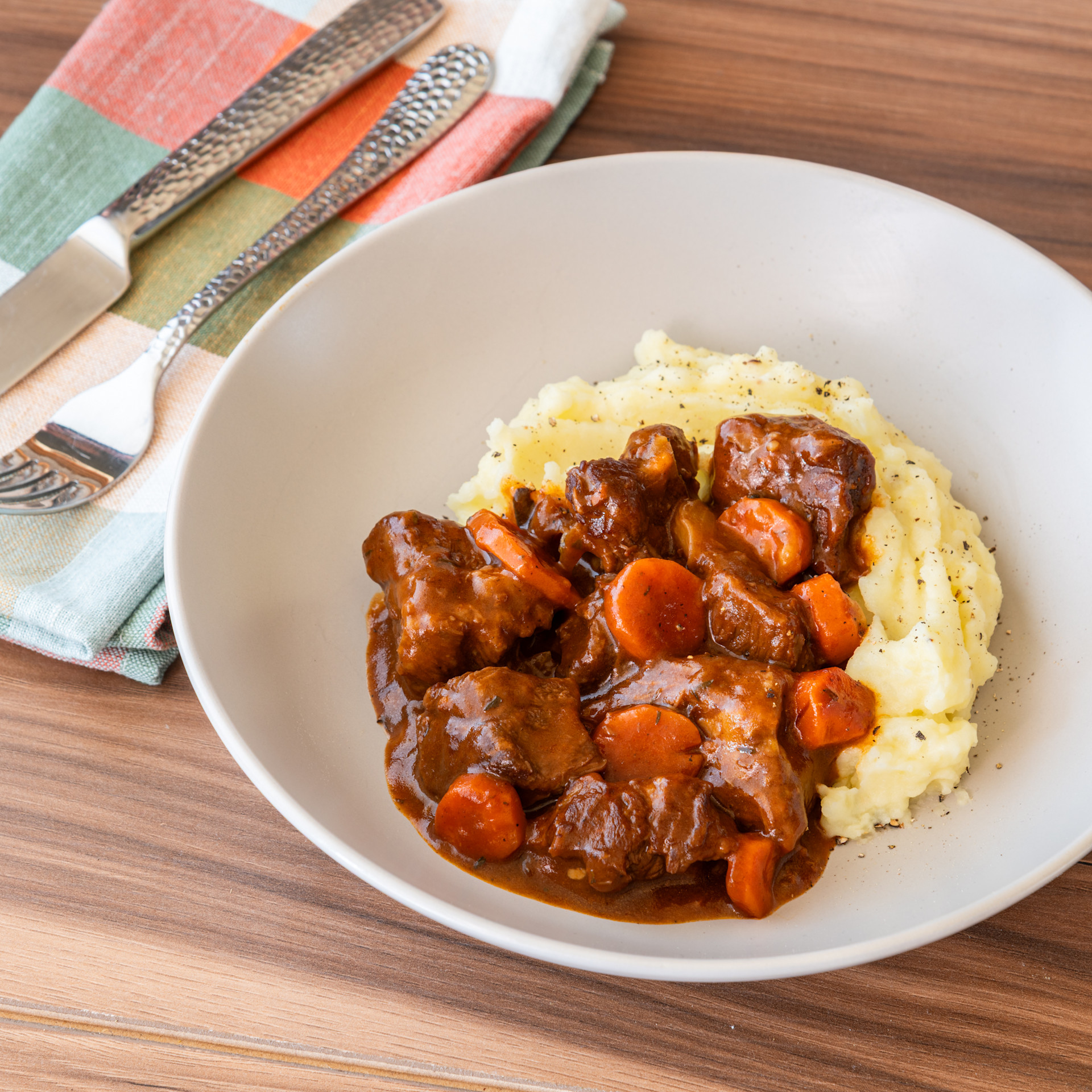 a white bowl with mashed potatoes and red wine braised beef stew