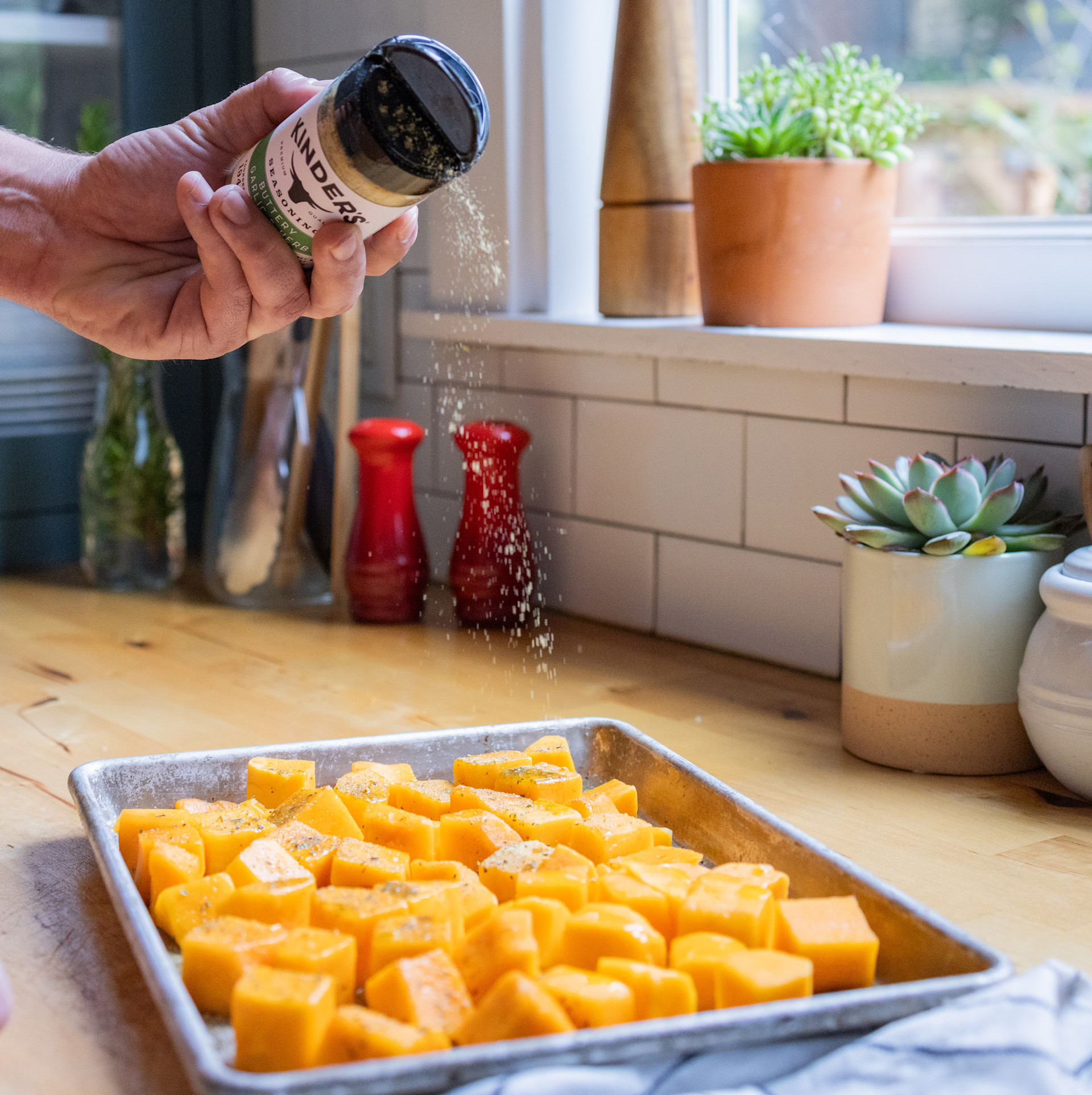 cubed butternut squash being sprinkled with seasoning