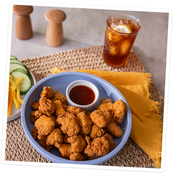 Chicken Bites on a blue plate with sliced vegetables
