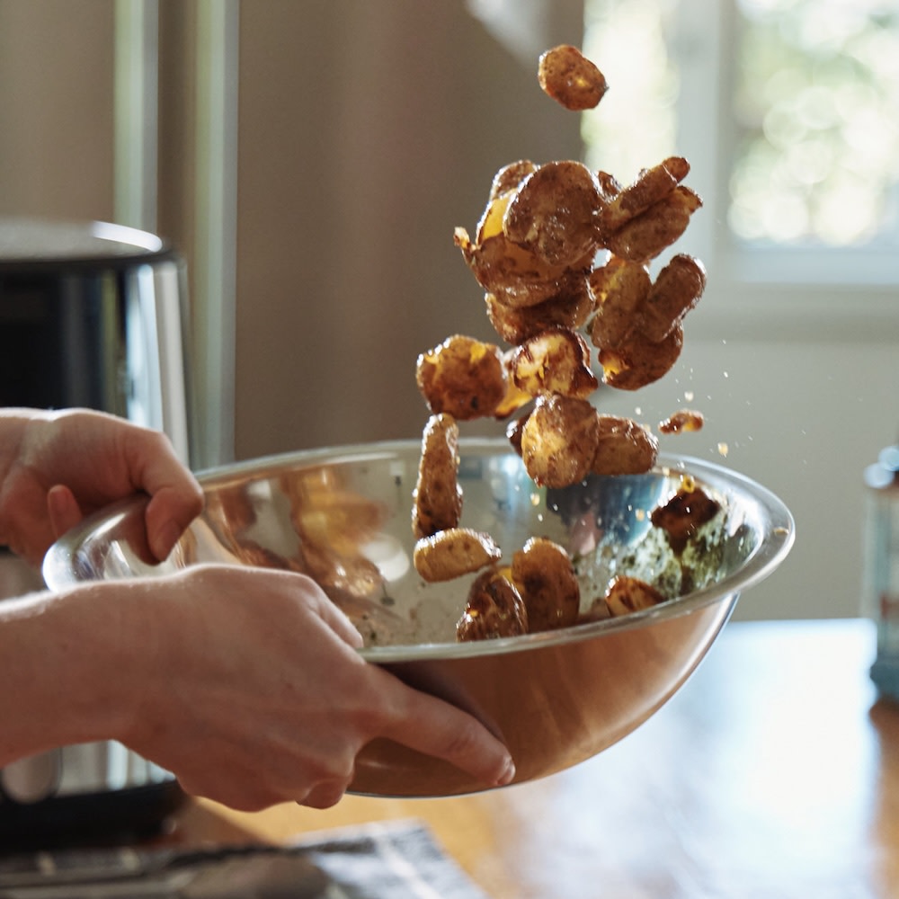 Smashed potatoes being tossed in seasoning