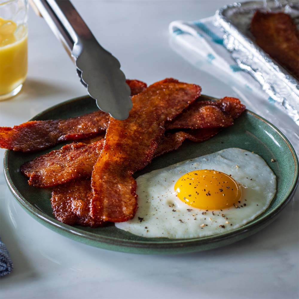 Candied bacon on a plate with sunny side up egg