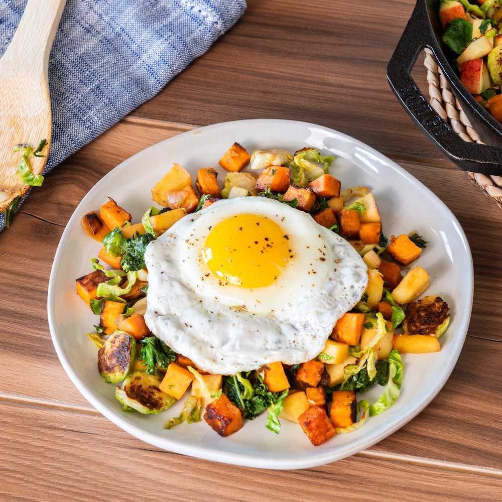 a white plate with a vegetable hash and fried egg on top
