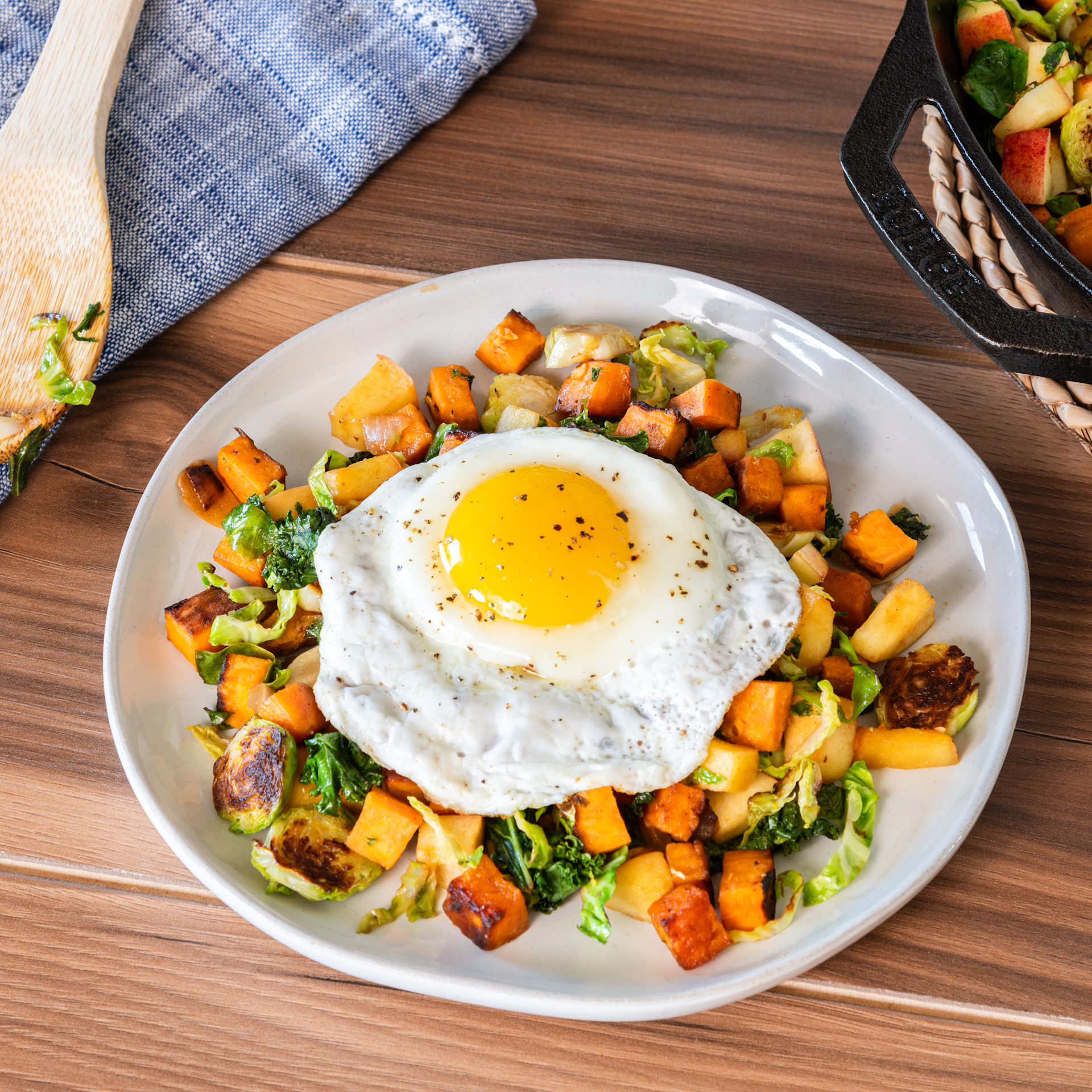 a white plate with a vegetable hash and fried egg on top