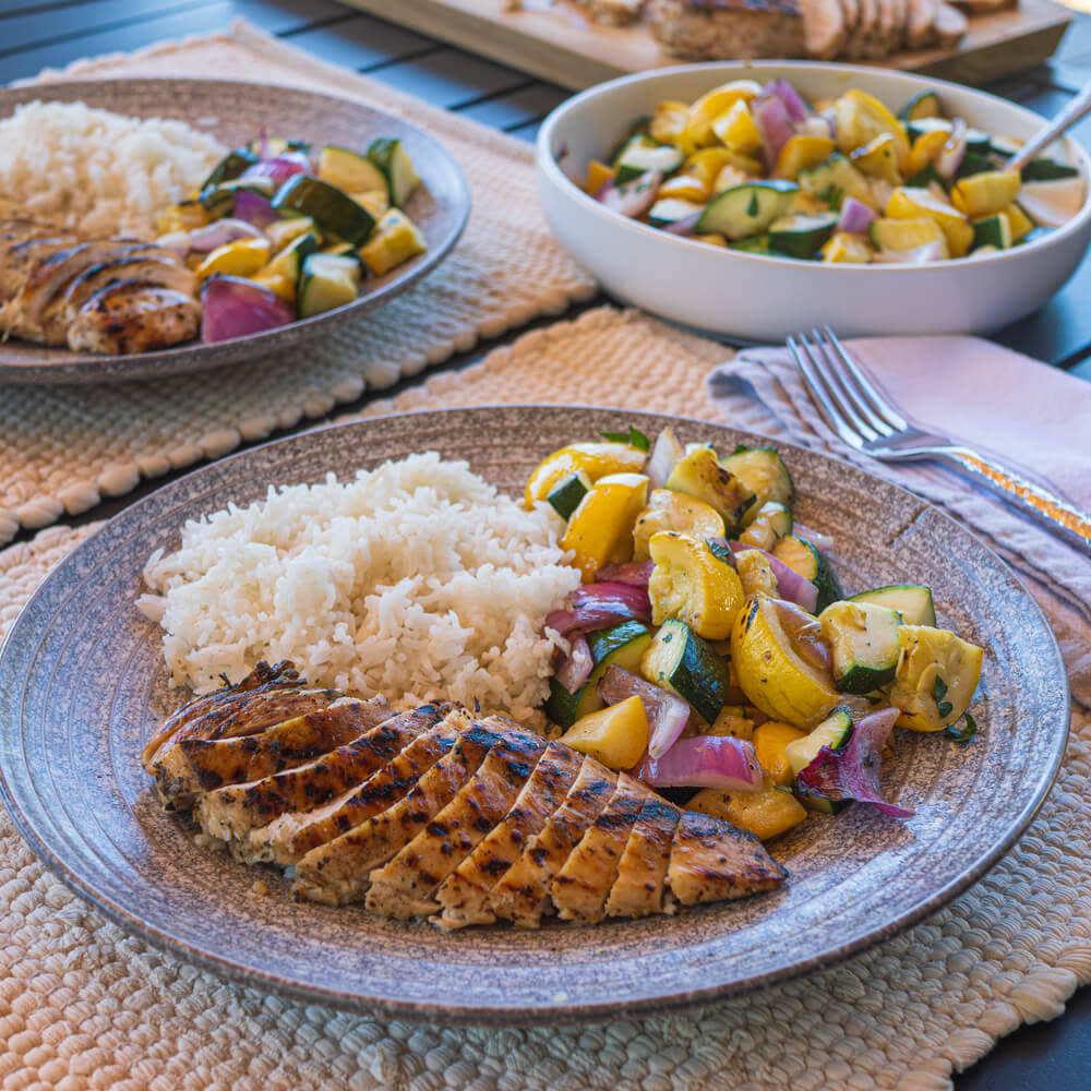 Plate with grilled chicken breast, rice and summer vegetables