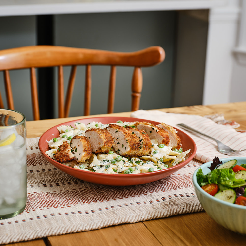 Crispy breaded chicken sliced on bowtie pasta with peas