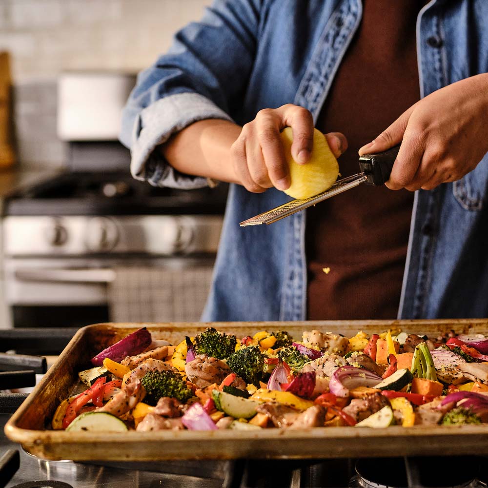 Zesting a lemon on sheet pan chicken and veggies