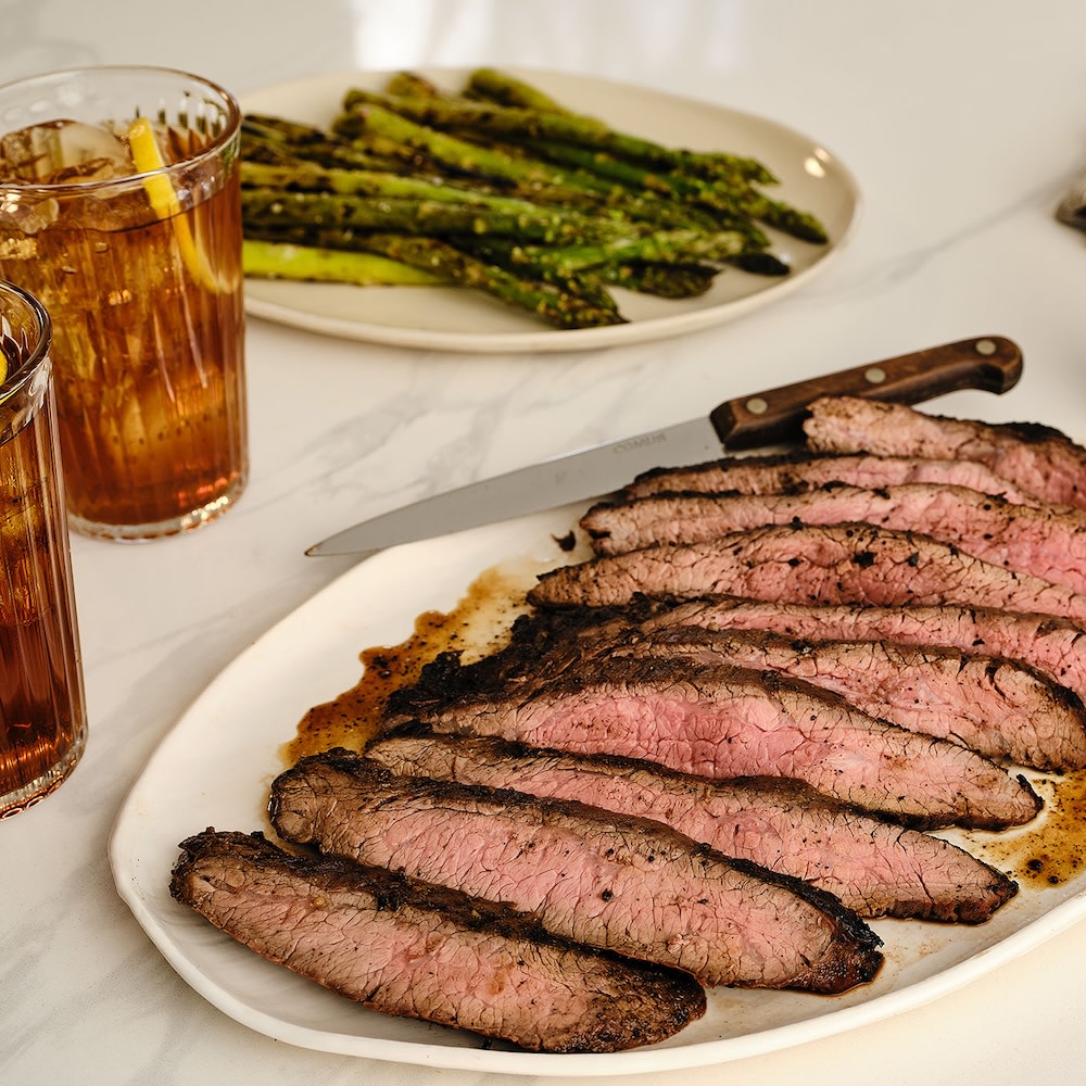 Grilled flank steak on white serving plate